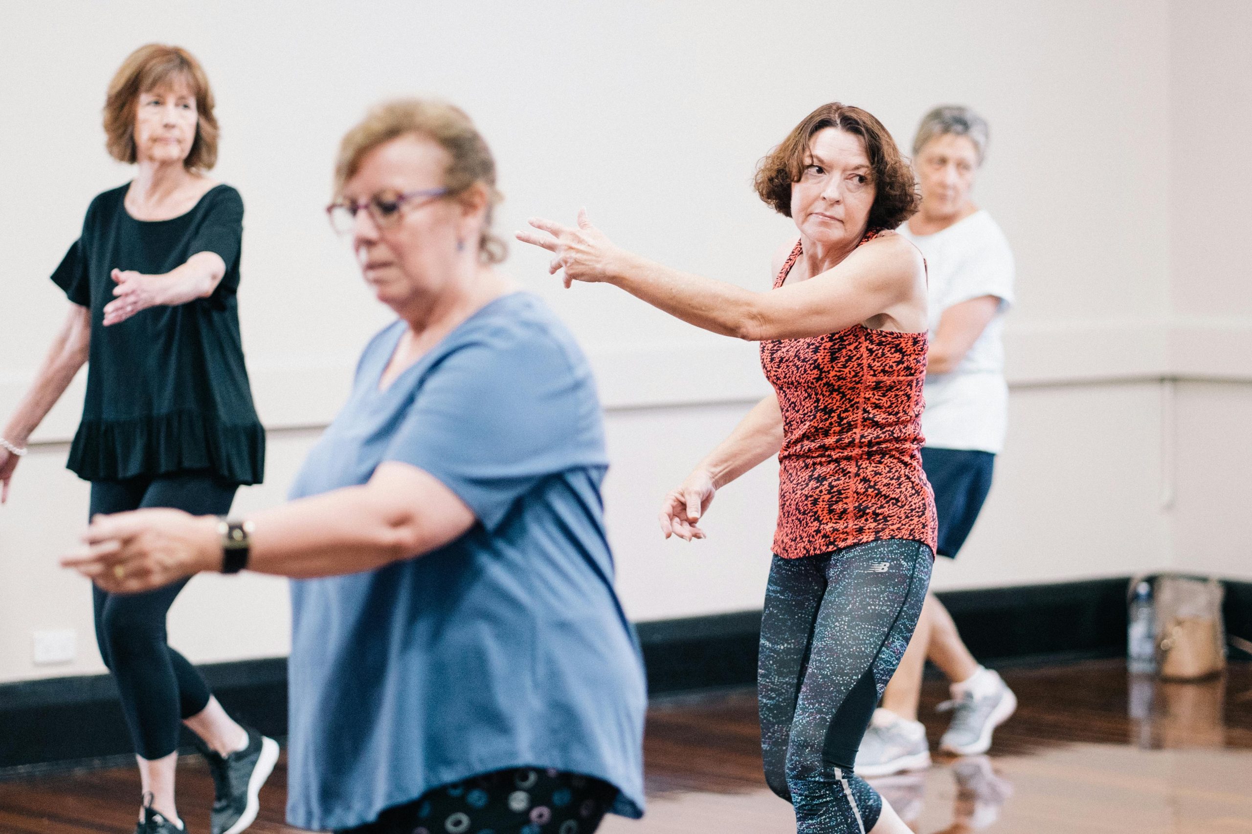 Senior women enjoying a group dance exercise in a fitness class, promoting health and togetherness.