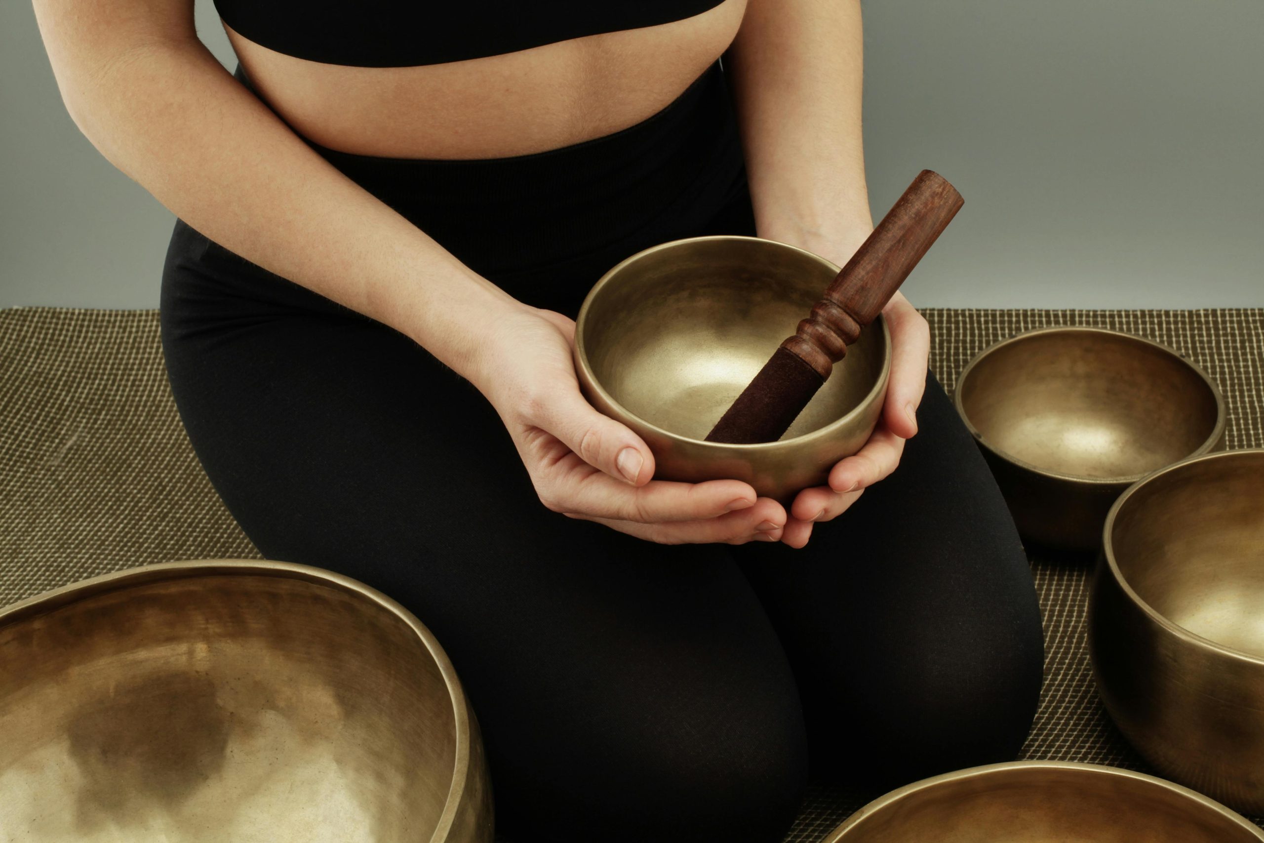 Close-up of a person using Tibetan singing bowls for meditation indoors.