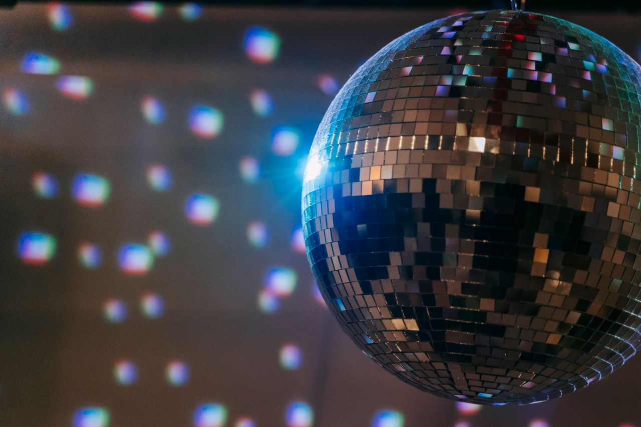 A vibrant disco ball reflecting colorful lights in a dimly lit room set for a lively atmosphere.