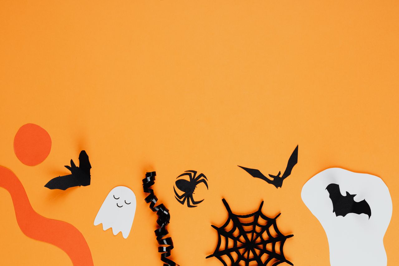 pexels-photo-5477624-5477624 Paper cutouts of bats, ghosts, and spiders on an orange background create a Halloween theme.