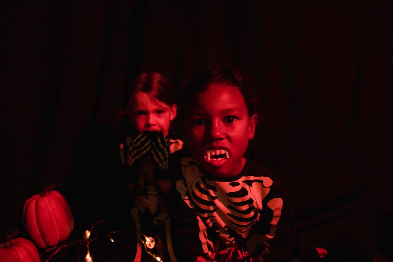 pexels-photo-9740418-9740418 Two kids in skeleton costumes with vampire teeth and pumpkins, perfect for Halloween-themed visuals.